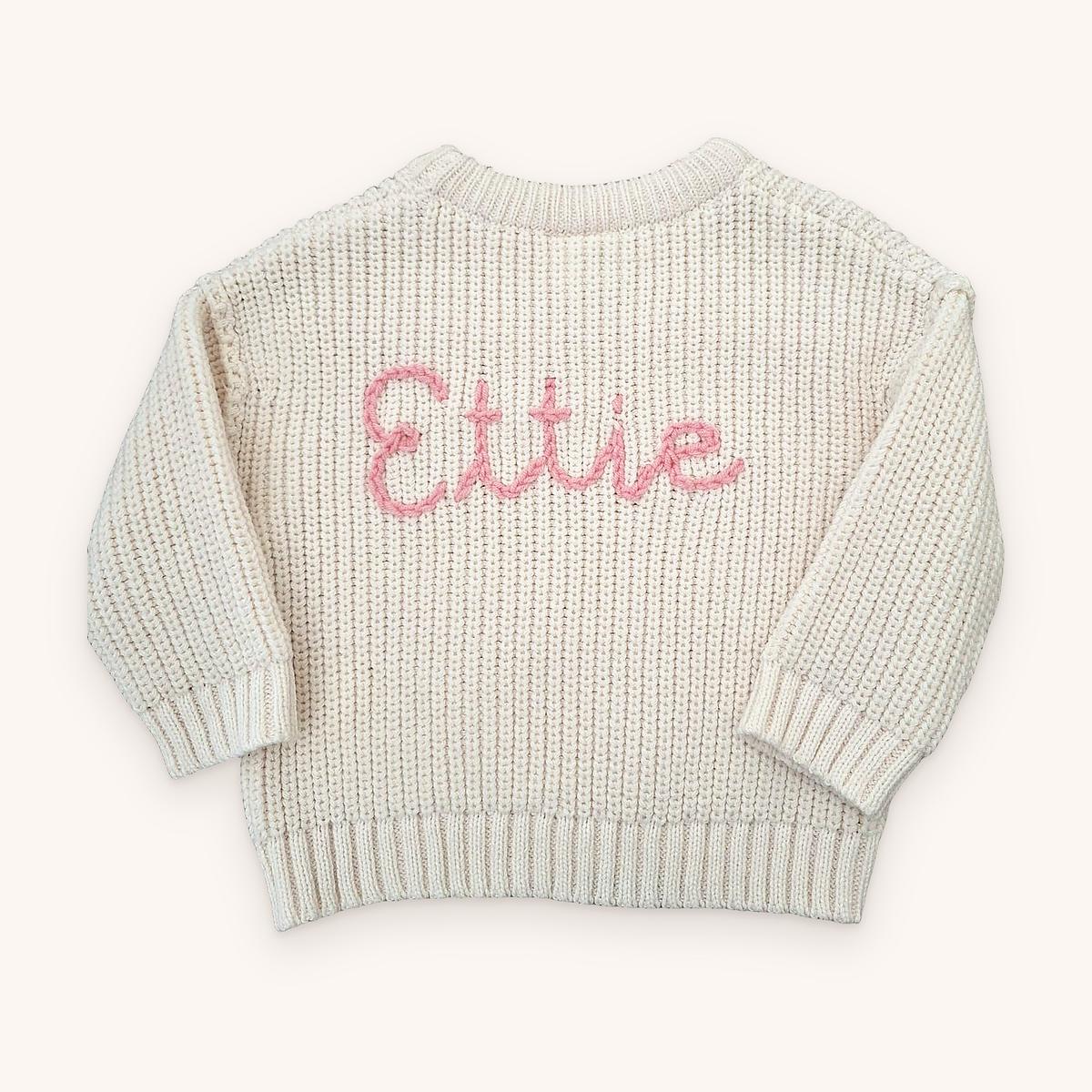 Cream chunky knit name jumper with Ettie hand-stitched in pink chain-stitch script